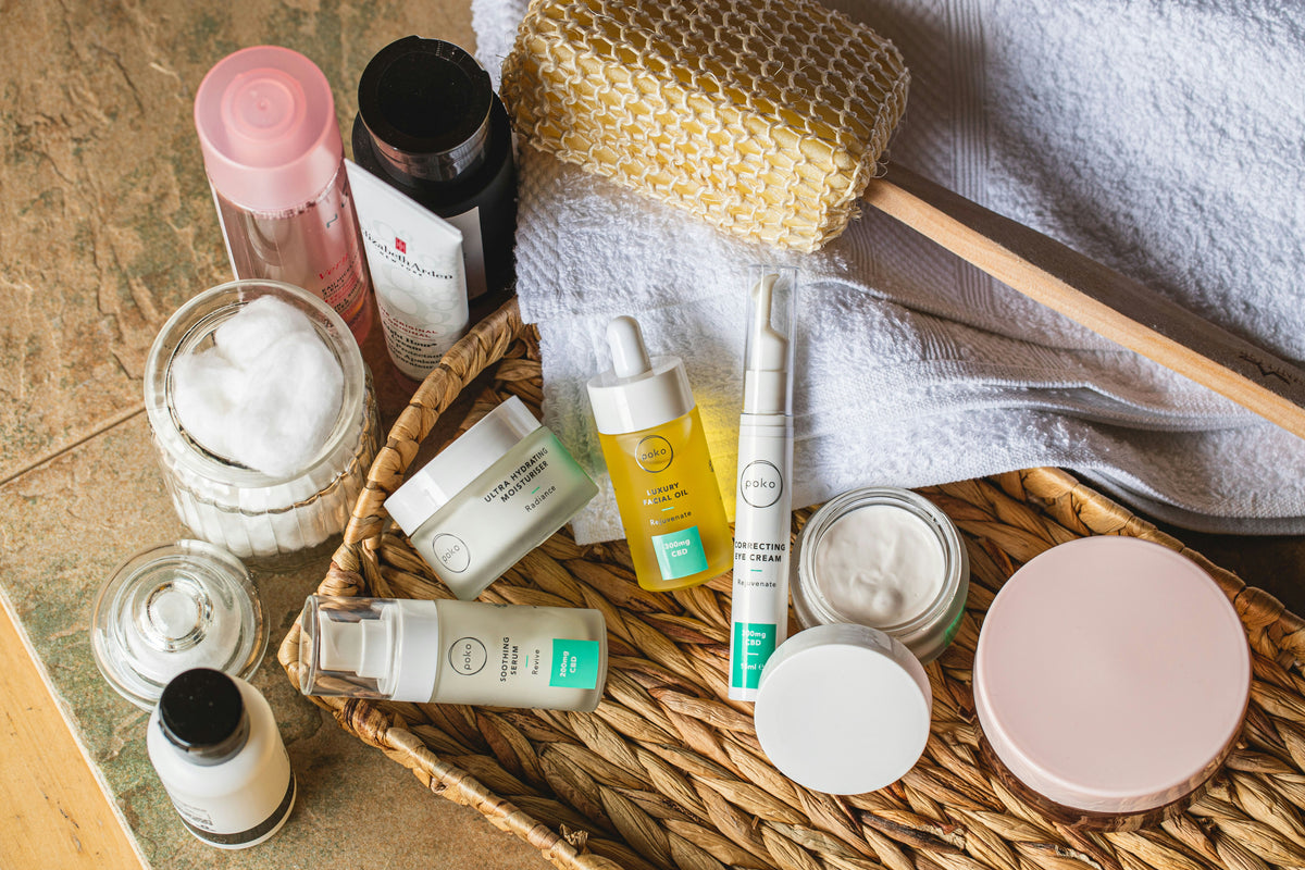 A warm flat lay of skincare bottles and jars in a woven basket